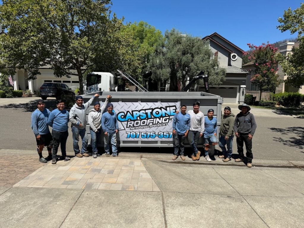 Capstone roofing team posing outside of branded dumpster