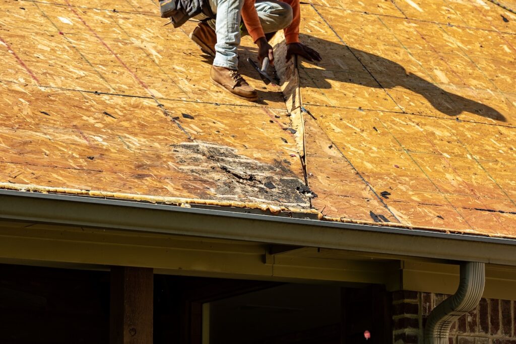 Worker hammers while repairing roof