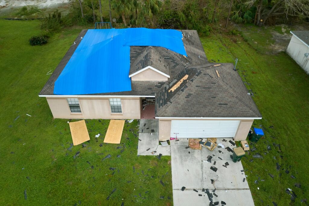 Top view of leaking house roof covered with protective tarp sheets against rain water leaks 