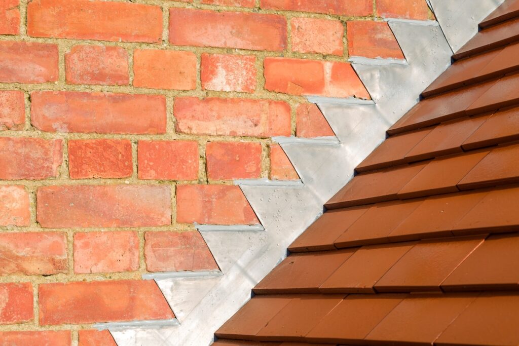 Closeup of new plain red clay tiles and lead flashing on a pitched roof