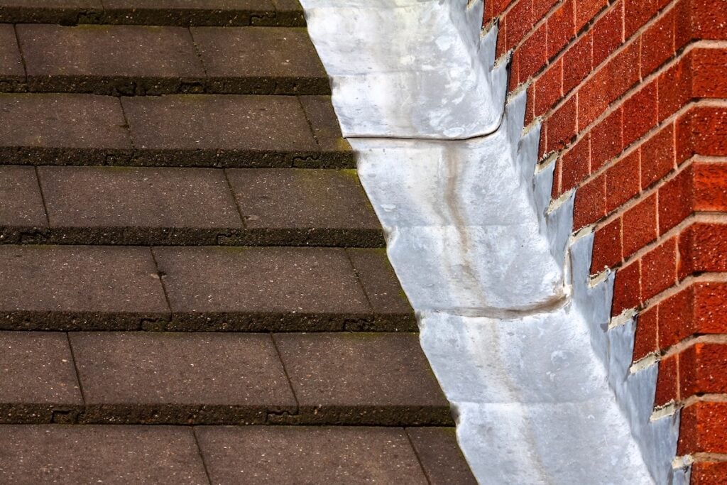 Stepped lead flashing roof gulley creating a water tight seal between roof tiles and brick wall