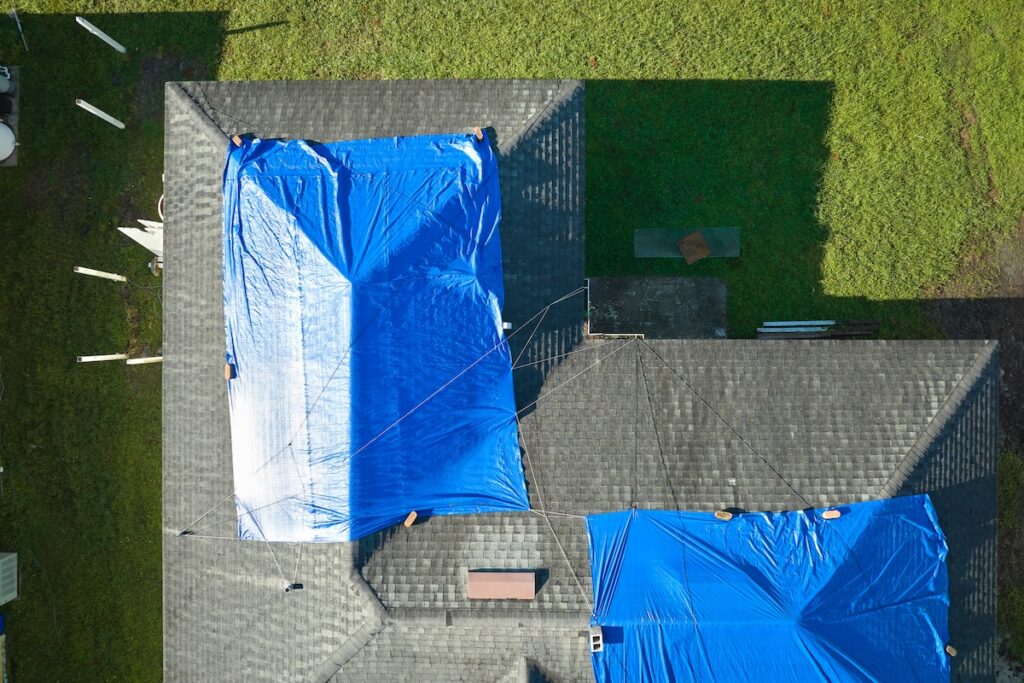 Top view of leaking house roof covered with protective tarp 