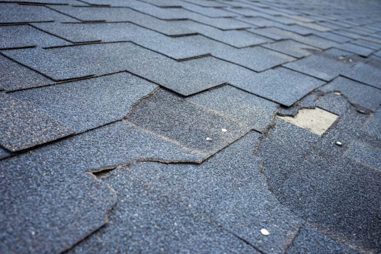 Сlose up view of bitumen shingles roof damage that needs repair.